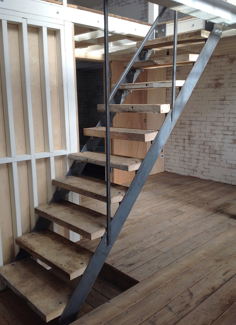  Reclaimed treads on bespoke steel staircase, reclaimed Victorian pine flooring, exposed framing with silver birch plywood hinged wall panels. Decorating with finishing. Warehouse conversion. Leyton E10, London 